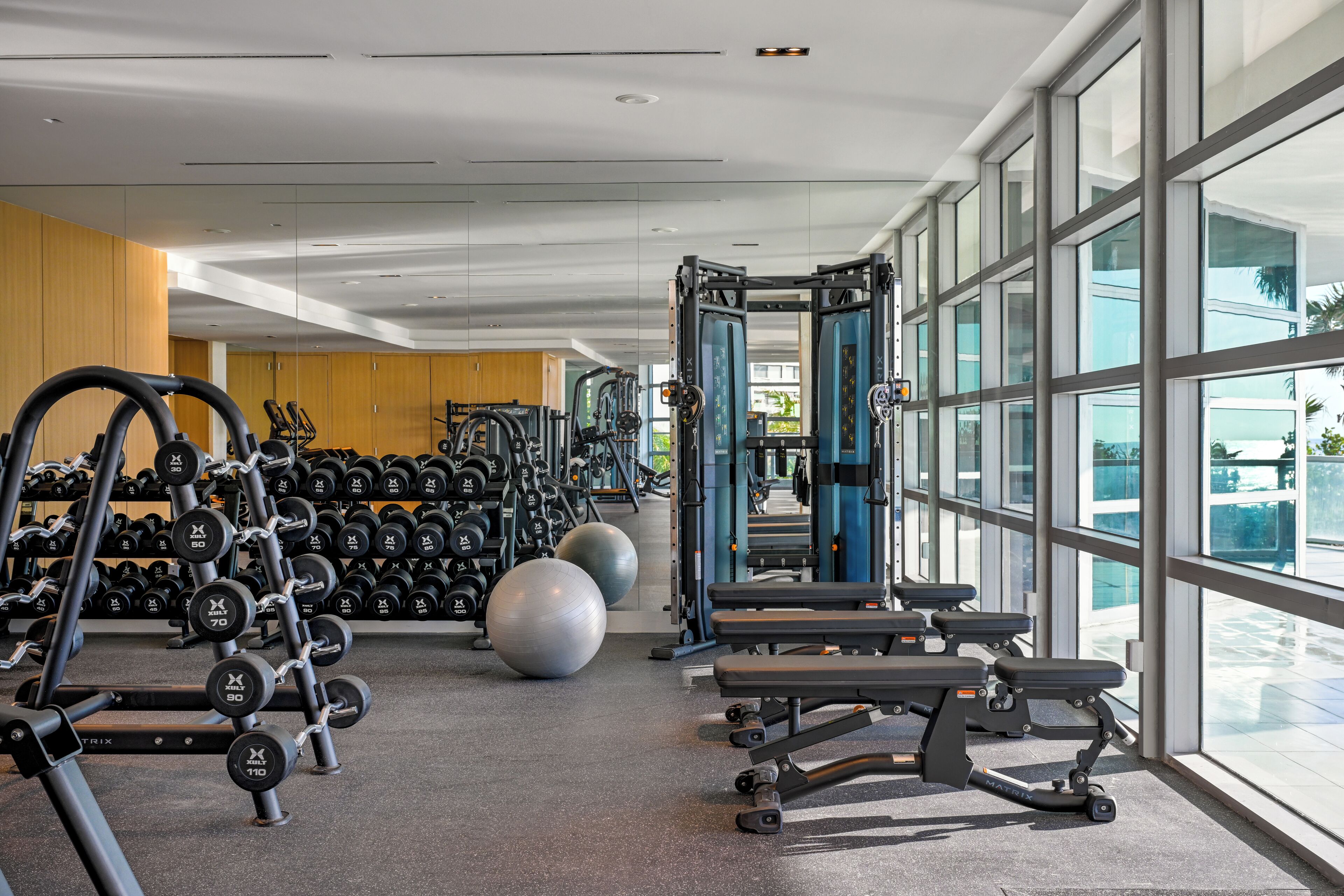 A gym with weightlifting equipment, exercise balls, and benches.