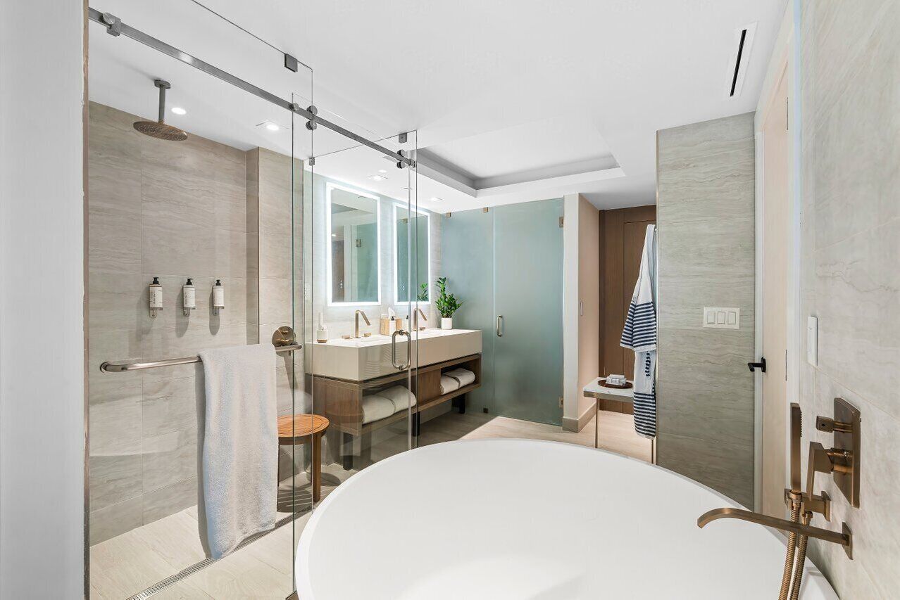 Un baño moderno con ducha de vidrio, bañera independiente y tocador con espejo.