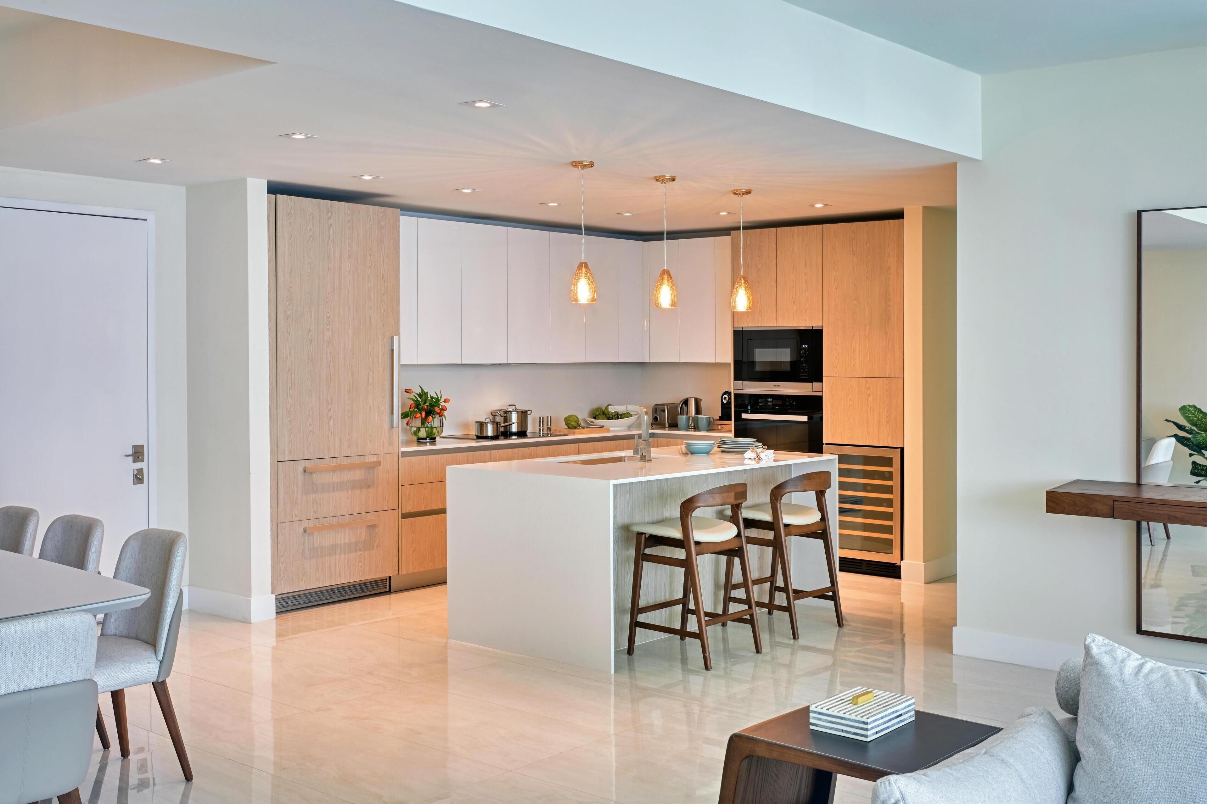 A modern kitchen with a central island, pendant lights, and wooden cabinetry.