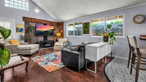 A living room with a fireplace, sofa, TV, and a dining area with a table and chairs.