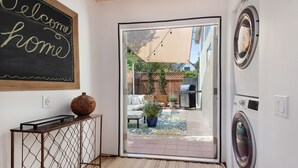 A laundry room with a washing machine, a drying machine, and a welcome sign on the wall.