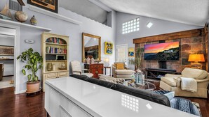 A modern living room with a large TV, a fireplace, and a dining area.