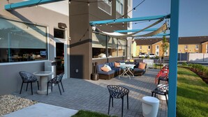 Un espace extérieur aménagé en patio, avec des sièges, une table et un coin abrité illuminé par des guirlandes lumineuses.