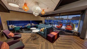 Un espace de détente moderne avec un canapé bleu, des fauteuils confortables et un plancher en bois.
