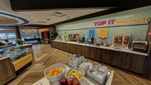 Un espace réservé au petit-déjeuner, avec une pancarte indiquant « TOP IT BREAKFAST » et divers aliments exposés.