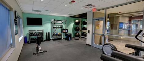 A gym with exercise equipment, a television, and a wall-mounted TV.