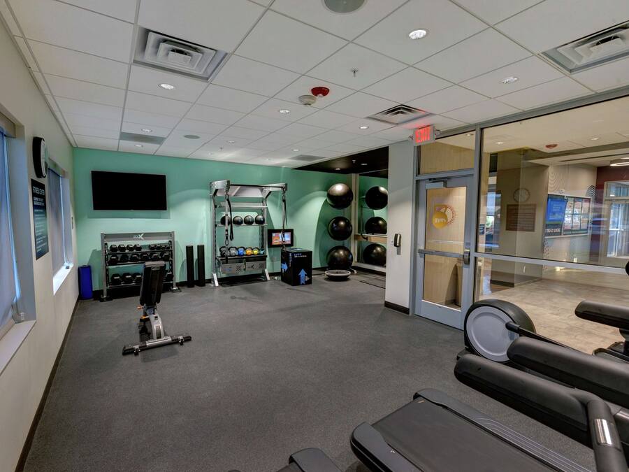 A gym with exercise equipment, a television, and a wall-mounted TV.