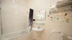 A bathroom with a bathtub, sink, toilet, and a mirror with a towel rack above it. - Yong Wong Hostel (Hengchun)
