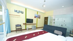 A hotel room with a bed, a TV, a desk, and a glass shower area. - Yong Wong Hostel (Hengchun)
