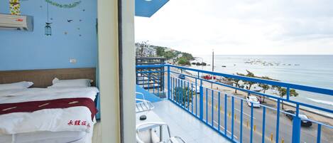 Quarto de hotel com varanda e vista para a praia. O quarto possui uma cama, uma cadeira e vista do mar.