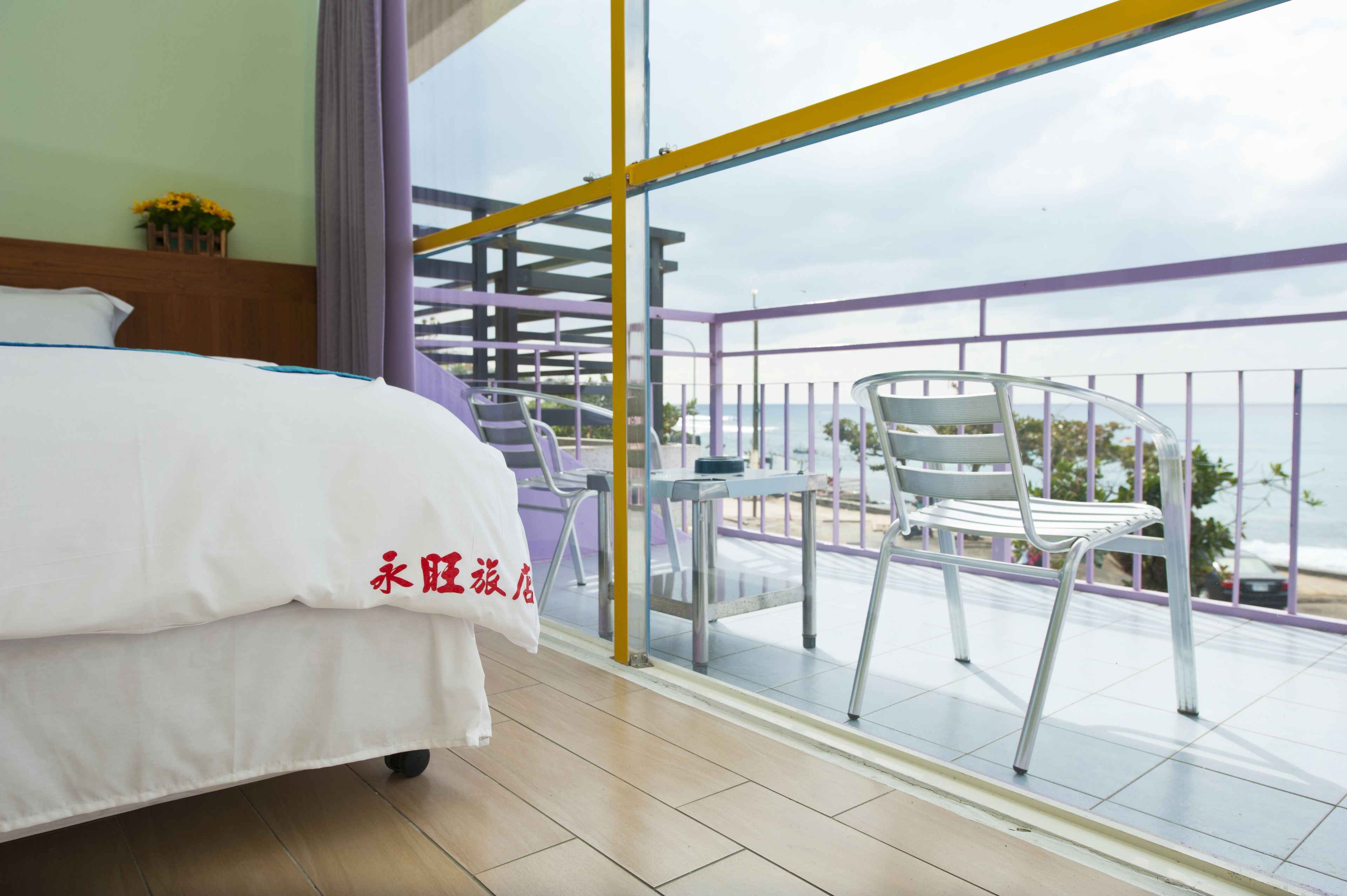 Habitación de hotel con cama, balcón y vista al mar, además de una silla.
