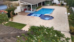 Ein Wohngrundstück mit Schwimmbad, überdachter Terrasse und einem Haus mit rotem Dach.