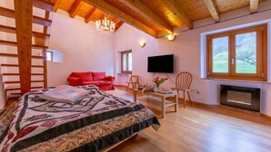 Une chambre à coucher avec un lit, une télévision, une cheminée et une grande fenêtre.