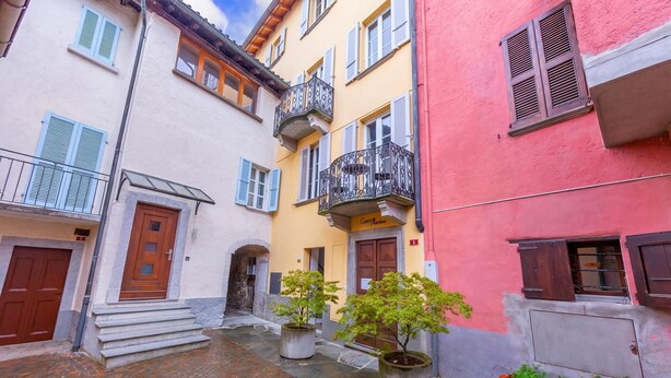 Une rue étroite bordée d’immeubles, avec une porte en bois et des plantes en pot.