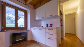 Une cuisine moderne avec des meubles blancs, un four encastré et une fenêtre donnant sur un jardin.