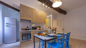 Une cuisine moderne avec des meubles en bois, un réfrigérateur en acier inoxydable et un coin repas avec des chaises bleues.