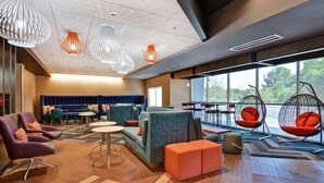A modern lounge area with seating, tables, and hanging chairs. - Tru by Hilton Middletown (Middletown)