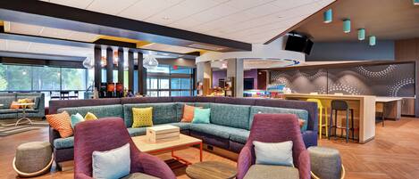A modern lounge area with a sectional sofa, armchairs, and a bar counter.