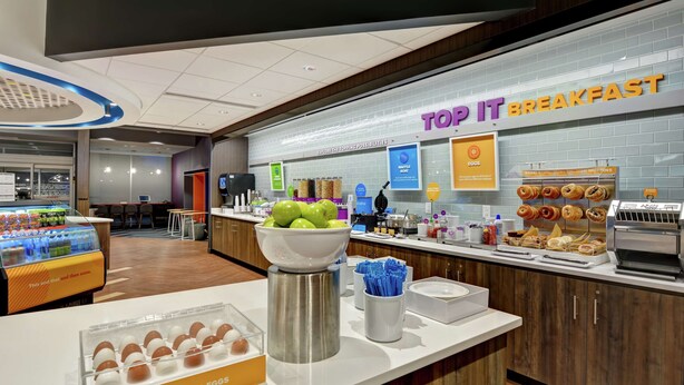 A breakfast area with a counter displaying hard-boiled eggs, a bowl of green apples, and various pastries. - Tru by Hilton Middletown (Middletown)