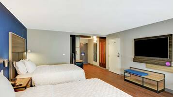 Camera d'albergo con due letti, una panca, una televisione e un ingresso che porta al bagno.