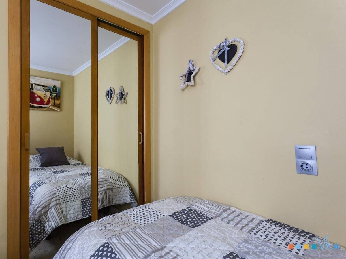 A bedroom with two beds, a mirror, and wall decorations.