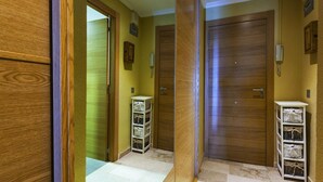 A hallway with wooden doors, a white storage unit, and a tiled floor. - NAIMA Apartment in Calpe – 1st line on Fosa Beach, for 4 people, terrace, swimming pool, Wi-Fi and air conditioning (Calpe)