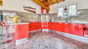 Een moderne keuken met rode kastjes, een centraal eiland en een houten plafond.