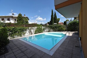 A rectangular swimming pool with a tiled deck, surrounded by greenery and a clear blue sky. - Casa Emma with Pool, Sirmione, Italy (Sirmione)