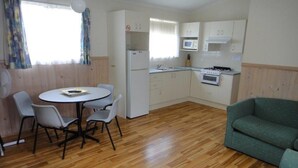 Ett kompakt bostadsutrymme med en matplats, ett litet kök och en soffa.