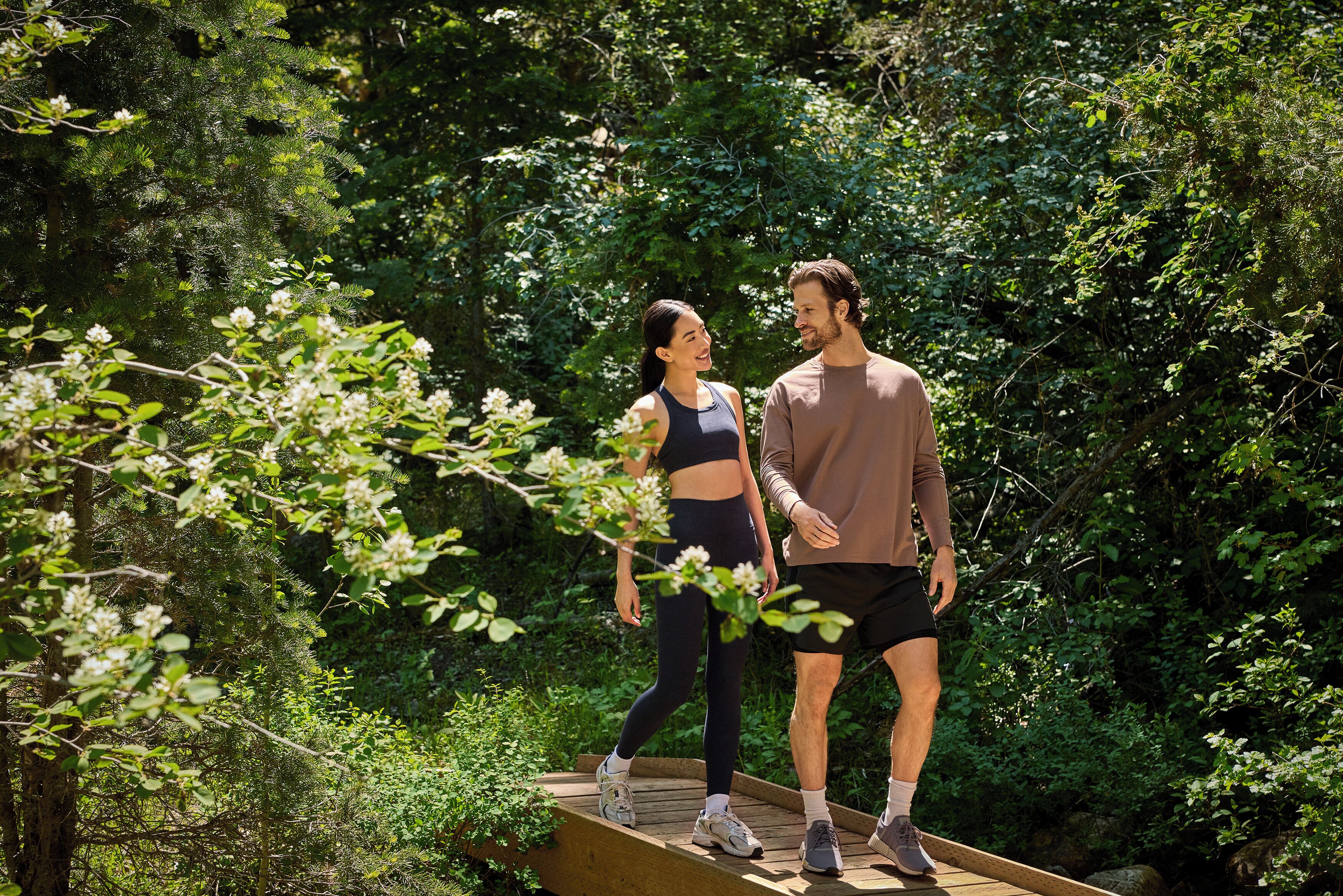 A couple standing on a wooden platform surrounded by dense greenery.
