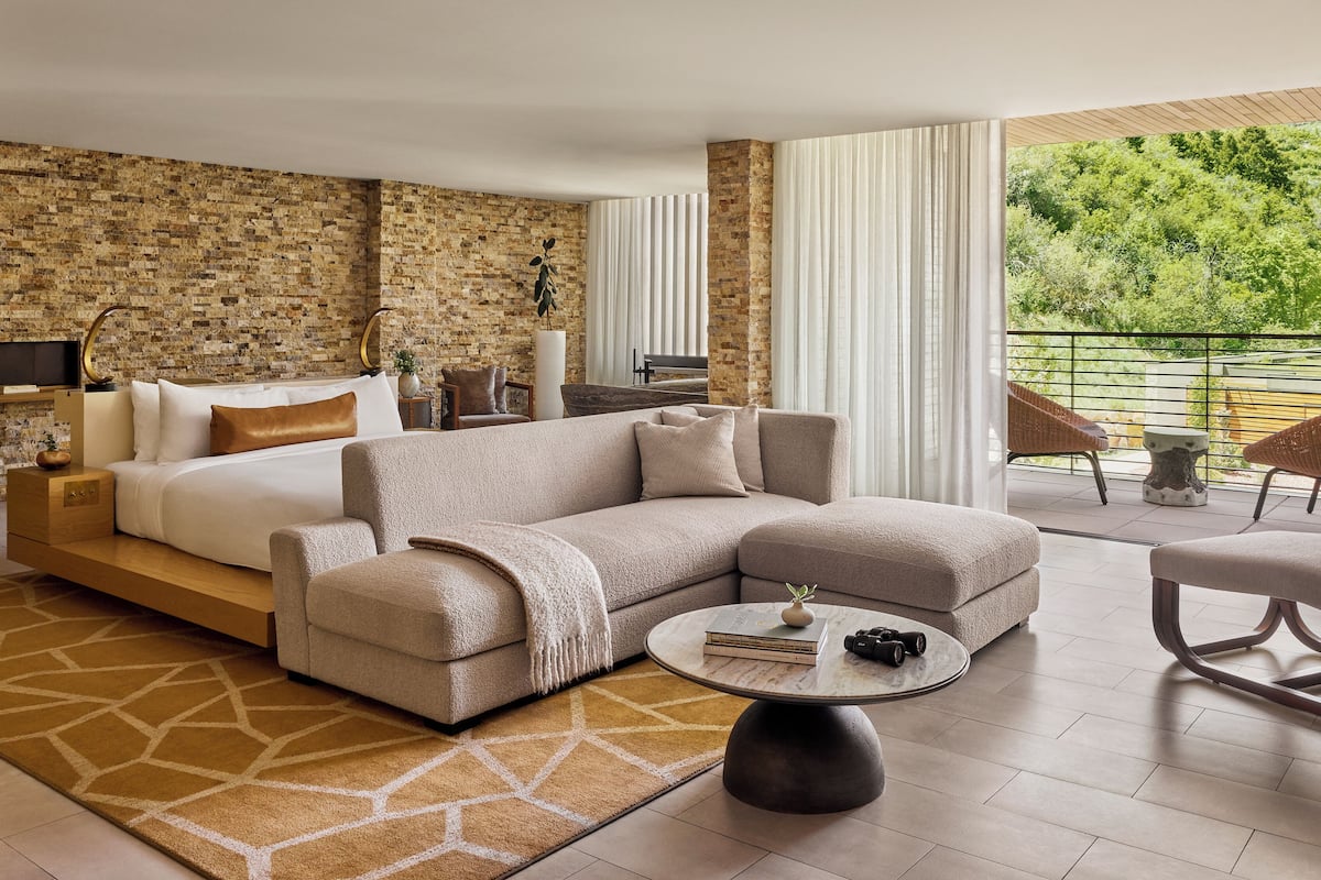 A modern living room with a sectional sofa, a coffee table, and a large window with a view of greenery.