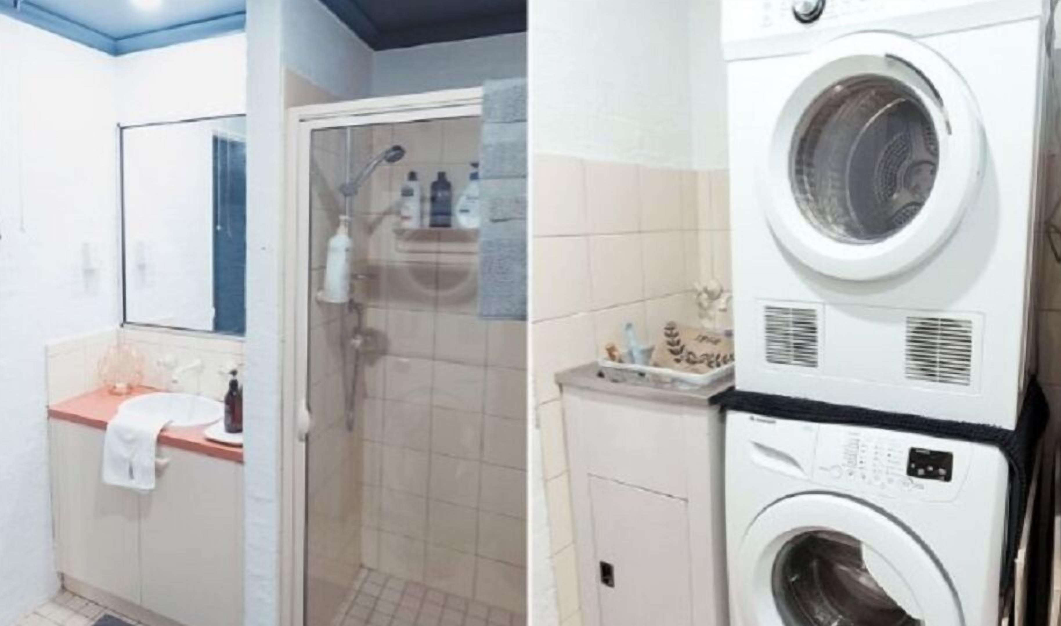 A bathroom with a shower, a sink, and a stacked washer and dryer.