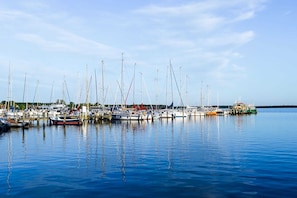 Ein Yachthafen mit mehreren angestaubten Booten, ruhigem Wasser und blauem Himmel.
