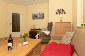 Ein gemütliches Wohnzimmer mit einem Holztisch, einer Couch, einem Sessel und einem Schrank.