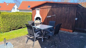 Eine Außenpatio mit Grill, Tisch und Stühlen.