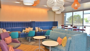 Een moderne lounge met blauwe en paarse zitplaatsen, ronde tafels en bijzondere hanglampen.