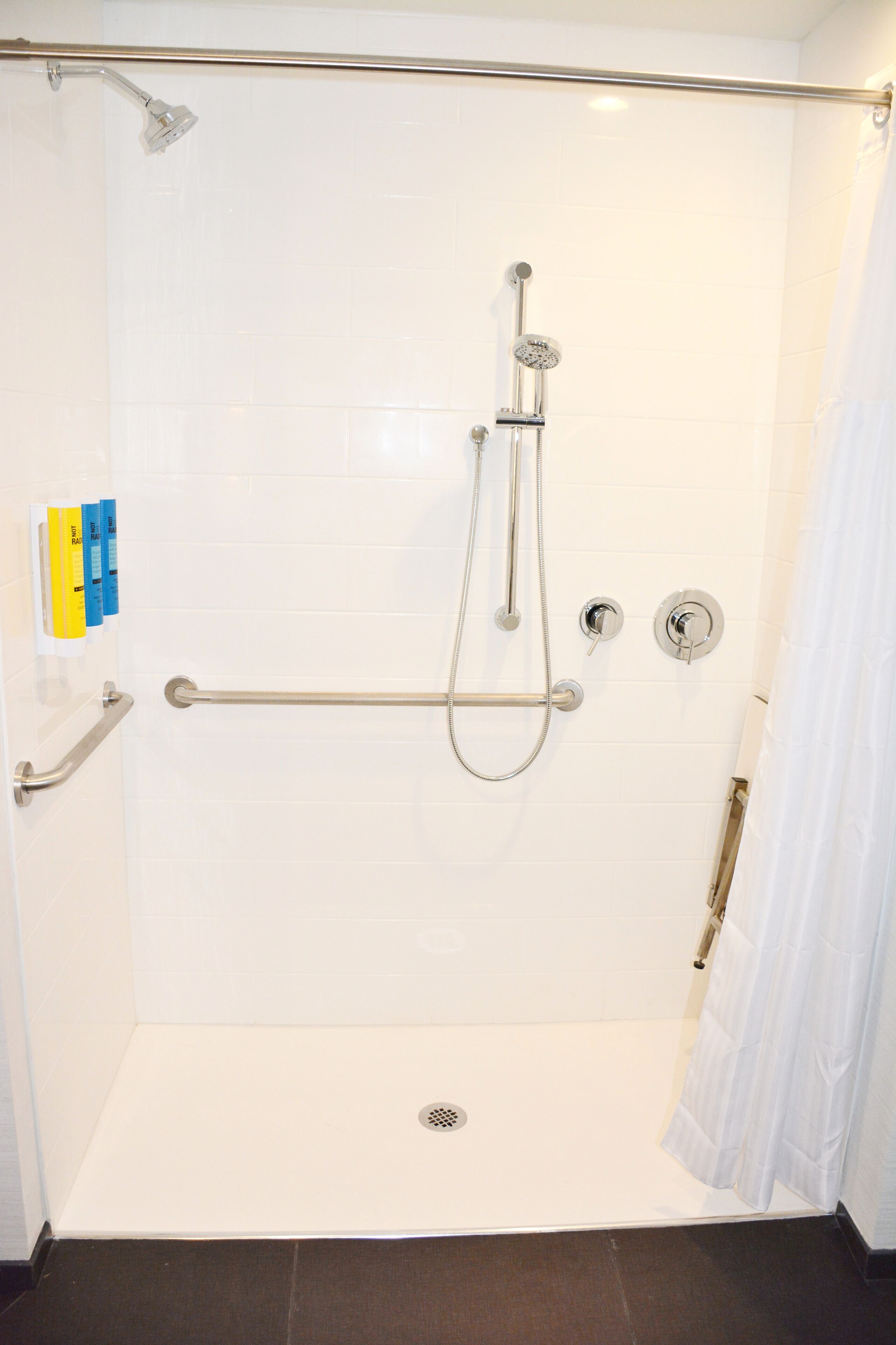Ducha a nivel con barra de apoyo, cabezal de ducha de mano y panel de control.