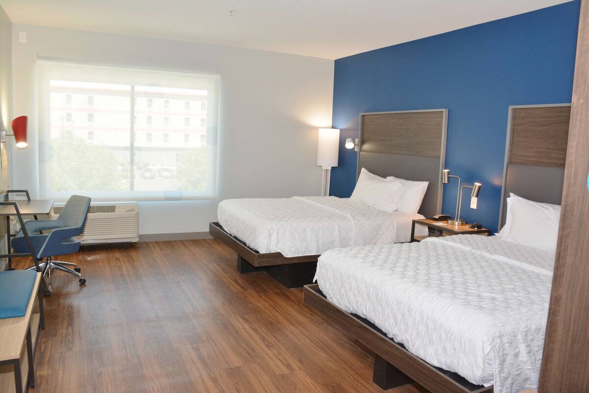 Een hotelkamer met twee bedden, een bureau en een stoel.