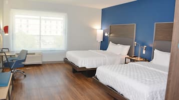 Une chambre d’hôtel avec deux lits, un bureau et une chaise.
