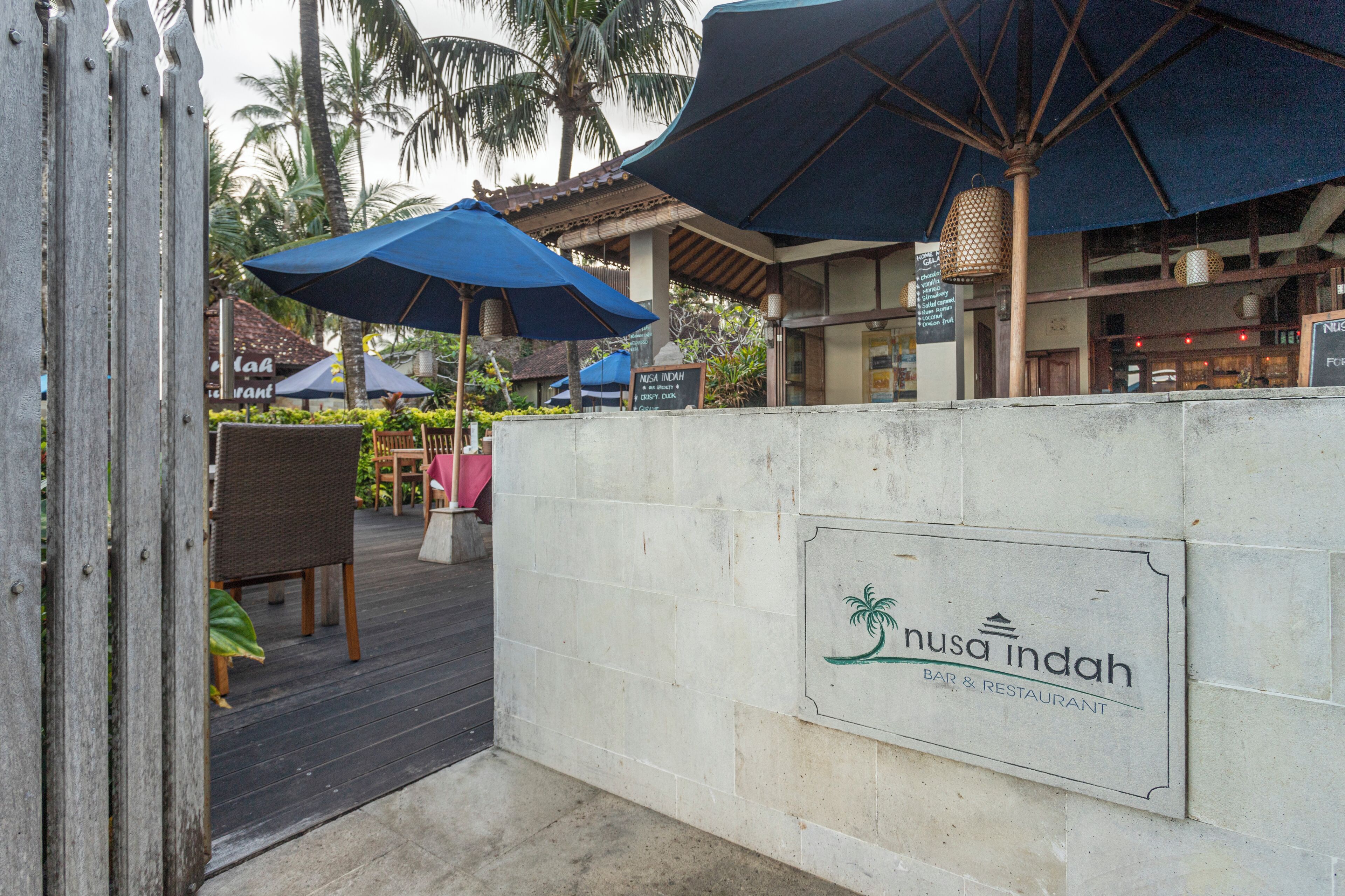 Un restaurant appelé « Nusa Indah » qui dispose d’une terrasse et de parasols.
