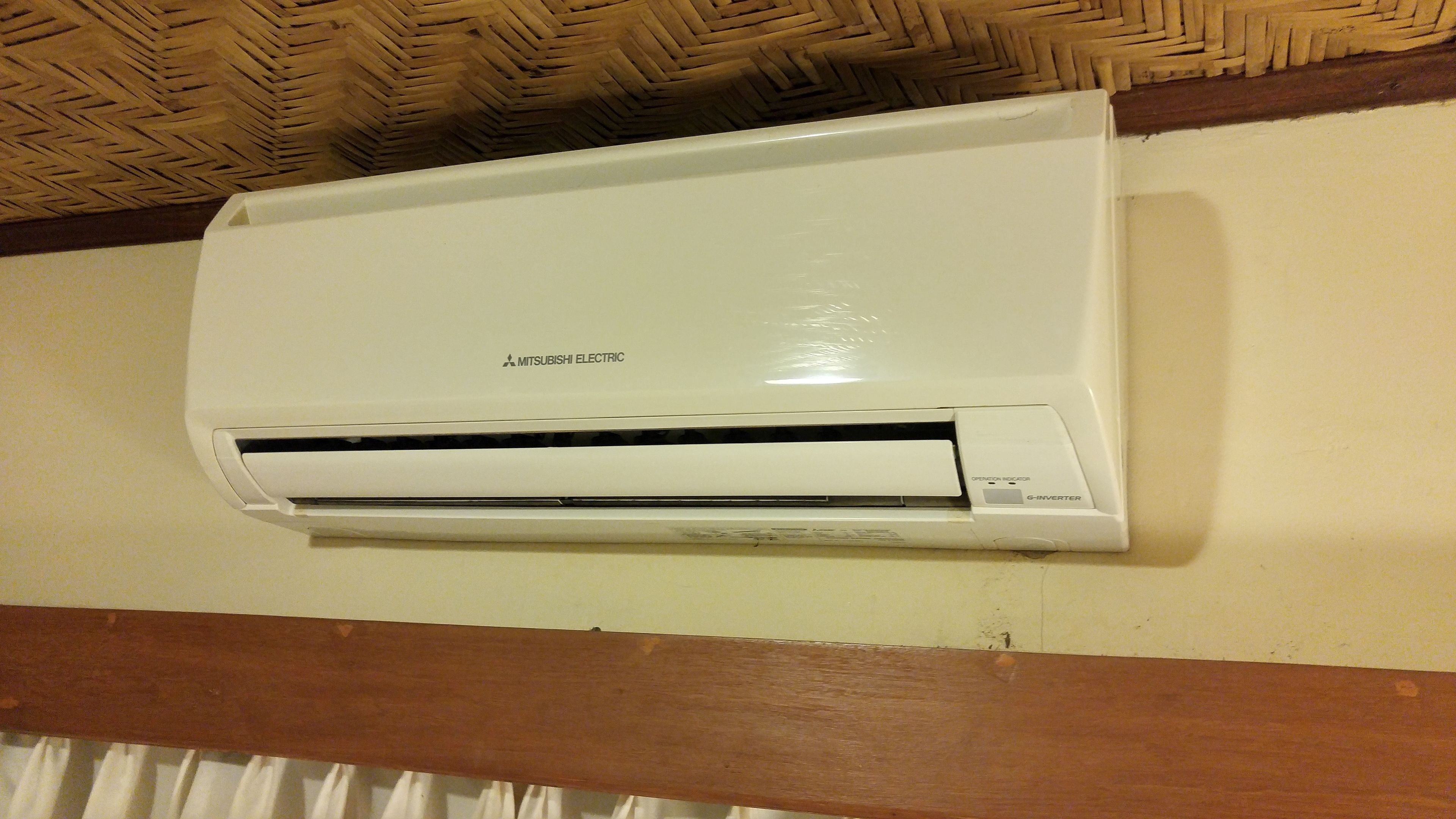 A Mitsubishi Electric air conditioner mounted on a wall with a wooden beam below.