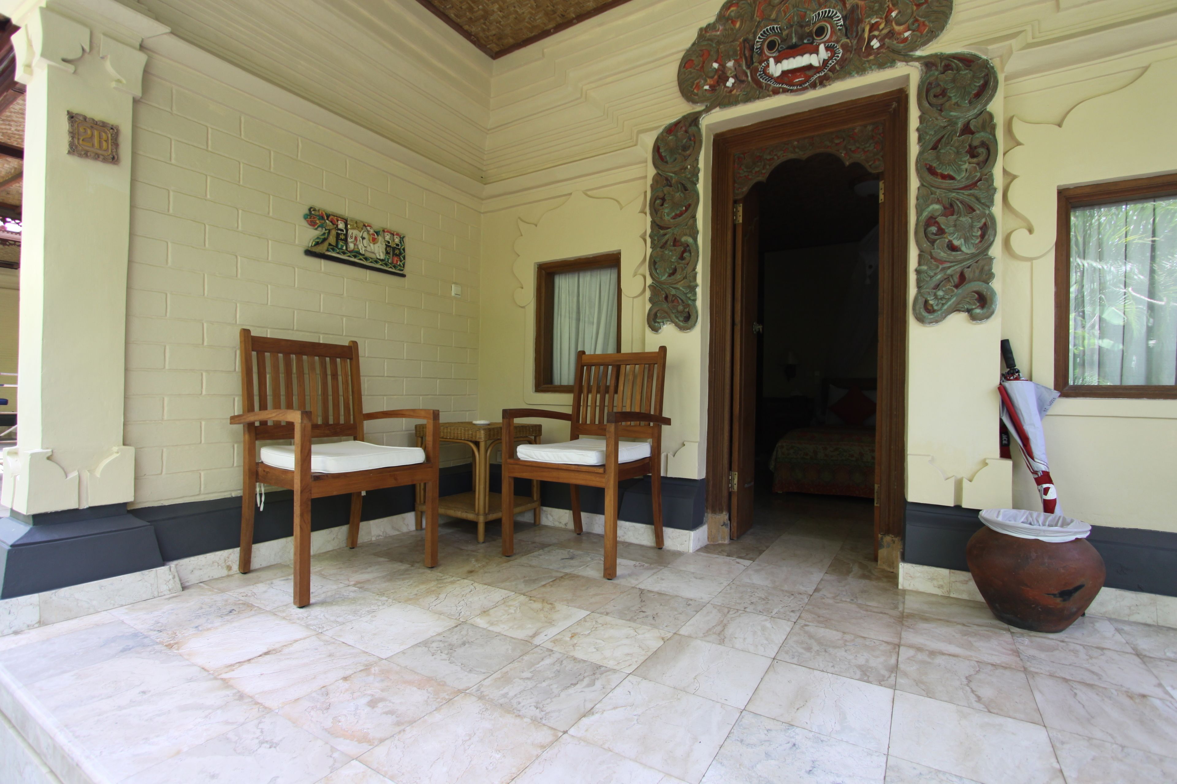 A room with a tiled floor, two wooden chairs, a small table, and a decorative door frame.