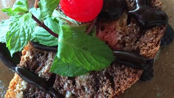 Una rebanada de pastel con chocolate y una cereza en la parte superior, decorada con hojas de menta.