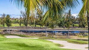 A golf course with sand bunkers, a water body, and trees.