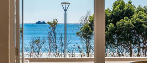 A beach view with a lamp post, trees, and a clear sky.