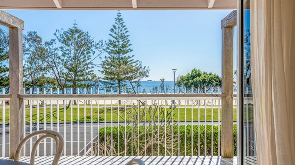 A balcony with a view of the sea, a chair, and a railing.