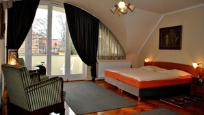 Un dormitorio con cama, una silla, una mesa y una ventana con cortinas.