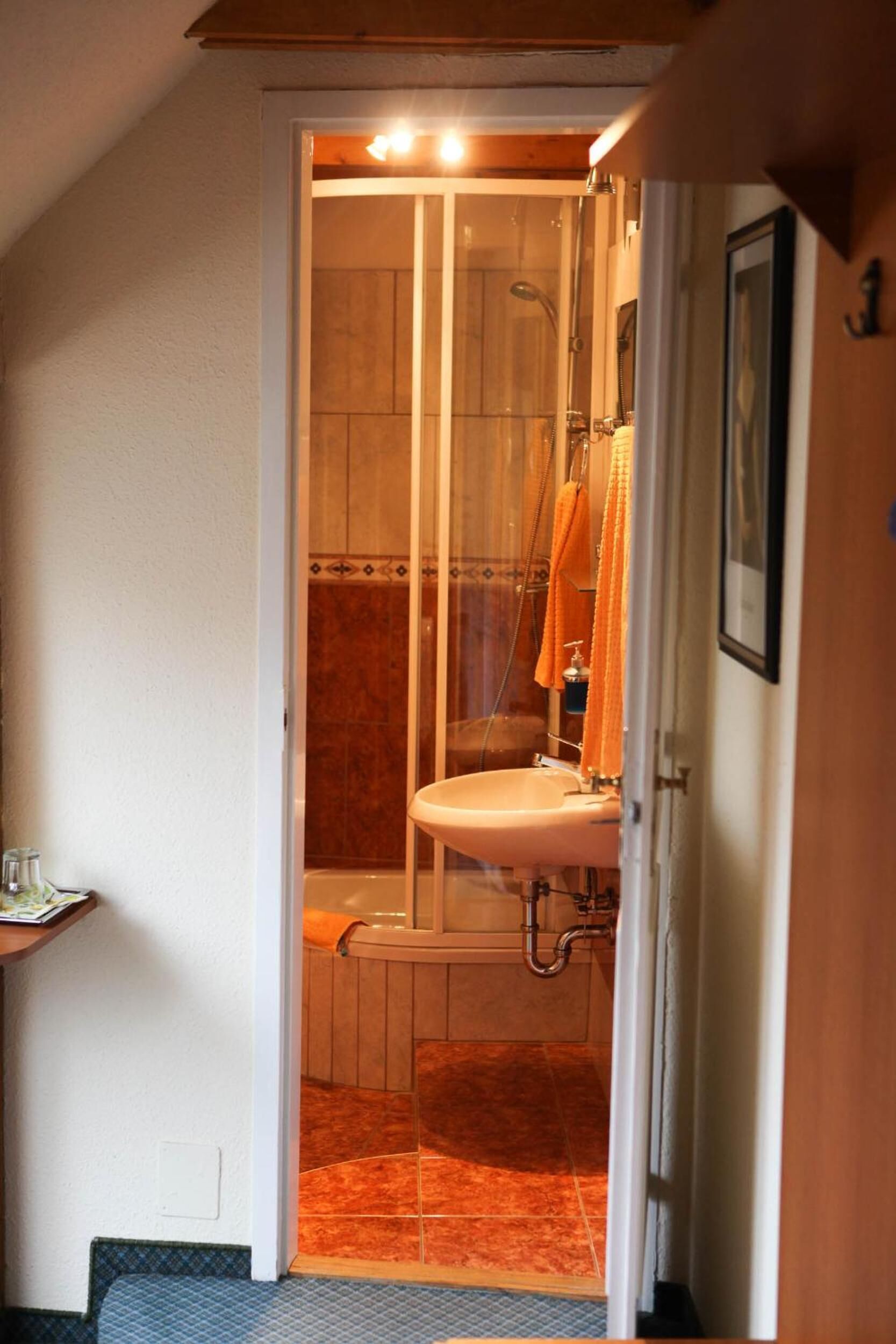 A narrow doorway leading to a bathroom with a shower, a sink, and a towel rack.