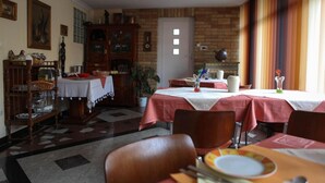Un comedor con mesas dispuestas para comer, un armario de madera y una puerta con ventana.