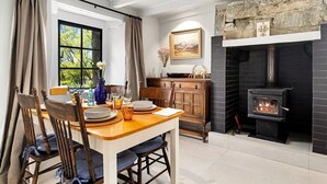 A dining area with a wooden table, chairs, and a fireplace. - Wanaka Stone Cottage - Wanaka Holiday Home (Wanaka)